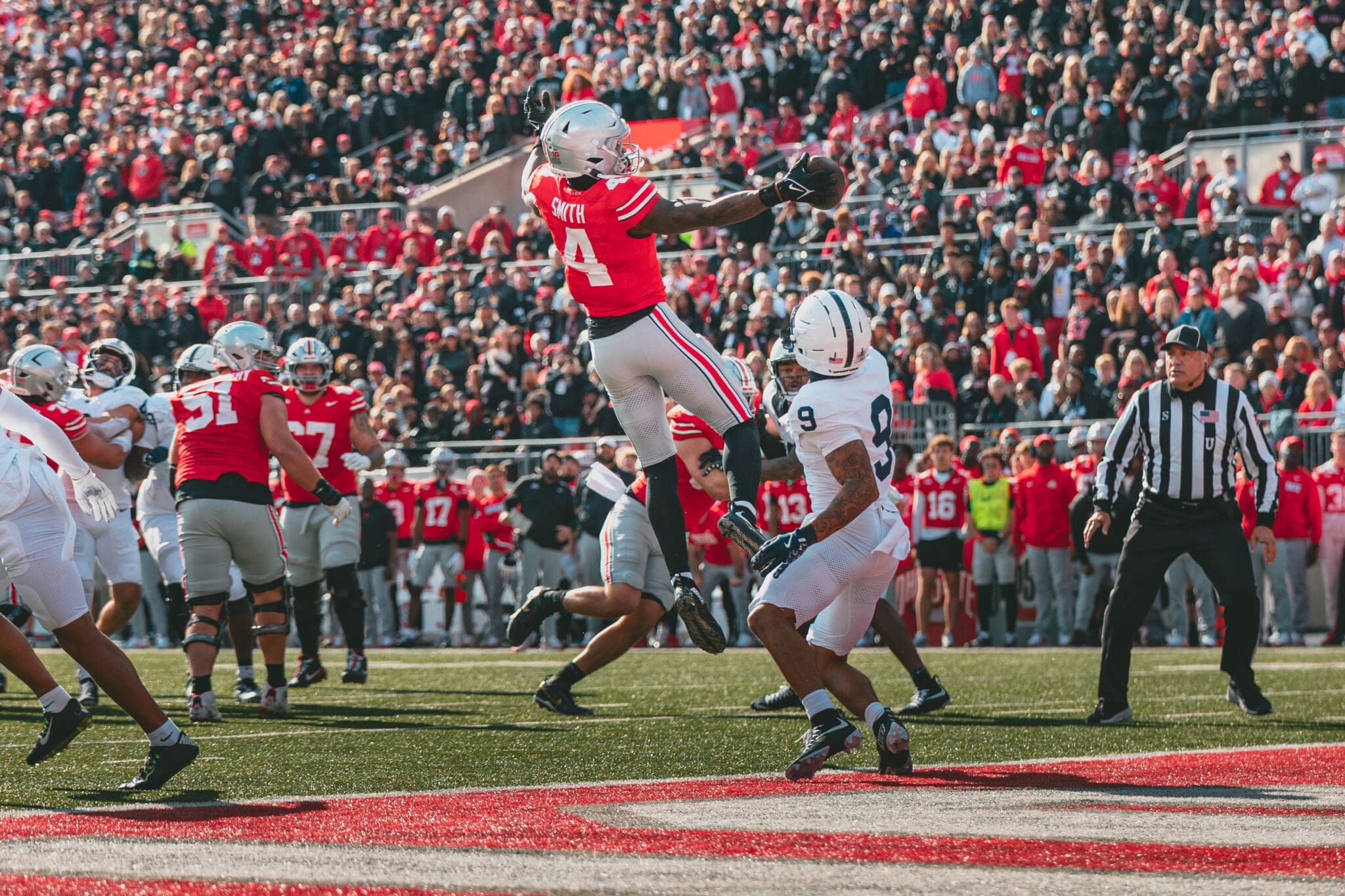 Jeremiah Smith leaps and stretches over a Penn State defender to make a one handed touchdown catch.